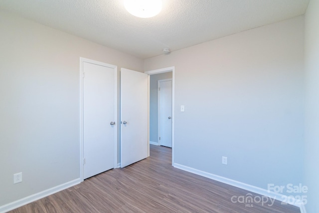 unfurnished bedroom featuring wood-type flooring, a closet, and a textured ceiling