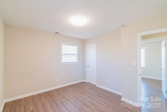 empty room with wood-type flooring and a textured ceiling