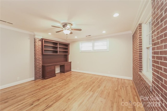 interior space featuring ceiling fan, built in desk, ornamental molding, light hardwood / wood-style floors, and brick wall