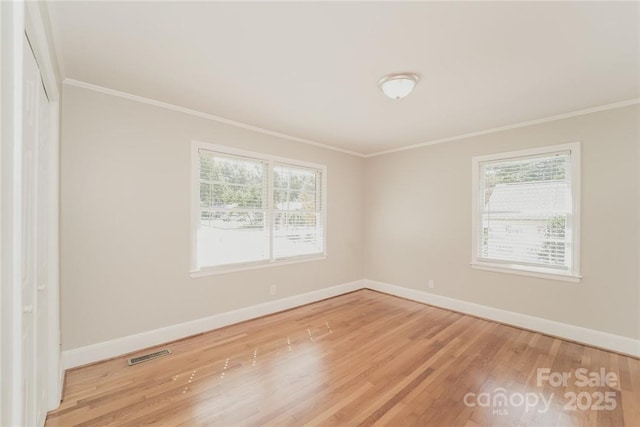 unfurnished room featuring ornamental molding, wood-type flooring, and plenty of natural light