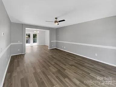 empty room with dark wood-type flooring and ceiling fan with notable chandelier