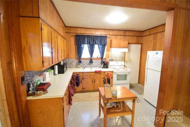 kitchen with white appliances, decorative backsplash, and wood walls