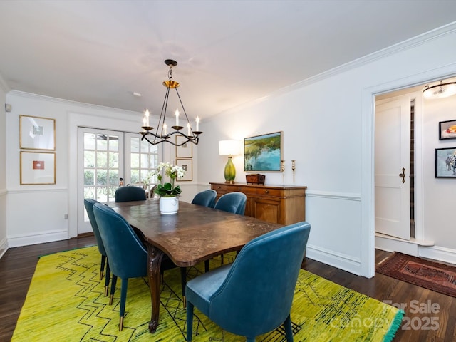 dining room with crown molding, an inviting chandelier, dark wood-type flooring, and french doors