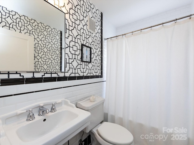 bathroom with walk in shower, toilet, sink, tile walls, and decorative backsplash