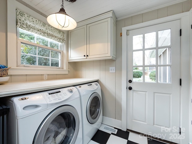 laundry area featuring cabinets, wooden walls, and washer and clothes dryer