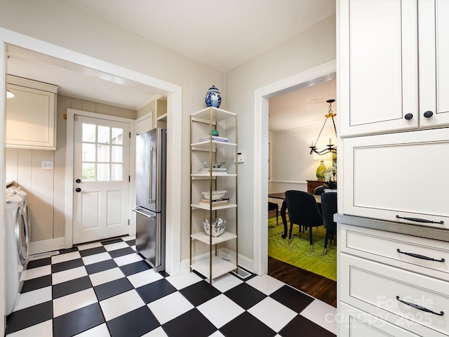 clothes washing area featuring separate washer and dryer, cabinets, and a chandelier