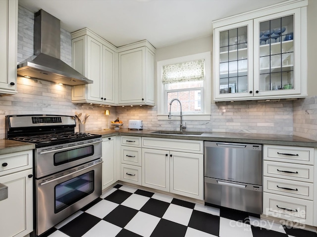 kitchen featuring appliances with stainless steel finishes, sink, decorative backsplash, and wall chimney range hood