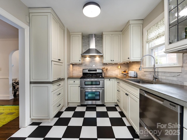 kitchen featuring stainless steel appliances, sink, backsplash, and wall chimney exhaust hood