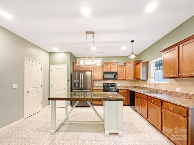 kitchen with sink, a breakfast bar, a center island, black appliances, and decorative light fixtures