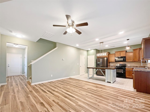 kitchen with pendant lighting, electric range, a kitchen breakfast bar, a kitchen island, and stainless steel fridge with ice dispenser