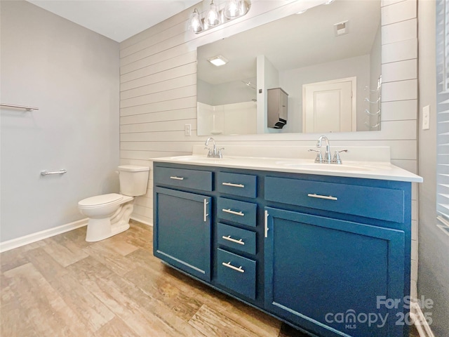 bathroom featuring wood-type flooring, vanity, wooden walls, and toilet