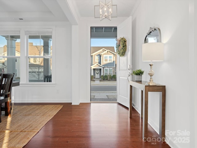 entrance foyer featuring crown molding, dark hardwood / wood-style flooring, and a chandelier