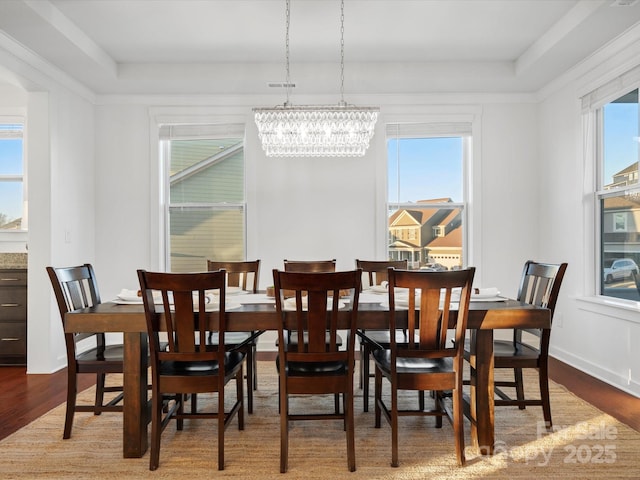 dining area with a tray ceiling, wood-type flooring, and a chandelier