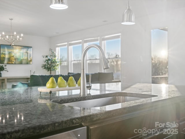 kitchen with dark stone countertops, sink, and pendant lighting