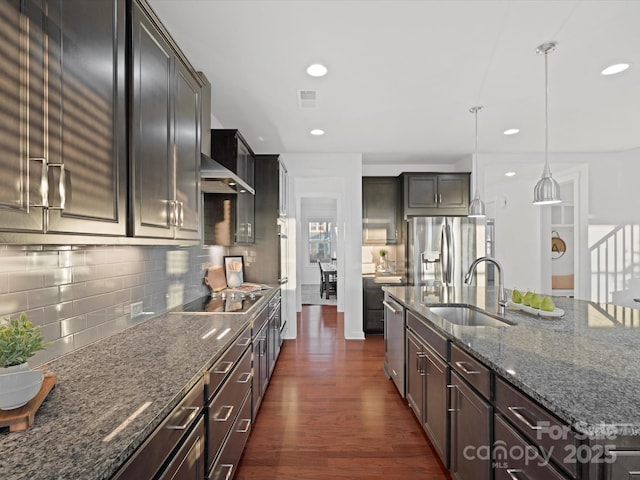 kitchen featuring dark hardwood / wood-style floors, pendant lighting, an island with sink, sink, and stainless steel appliances