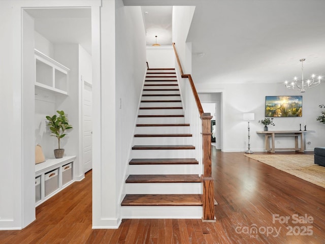 staircase featuring wood-type flooring and a chandelier