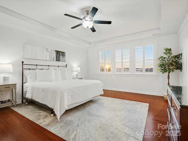 bedroom featuring dark hardwood / wood-style floors, ceiling fan, and a tray ceiling