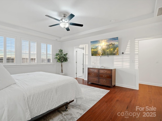 bedroom featuring dark wood-type flooring, ceiling fan, and a tray ceiling