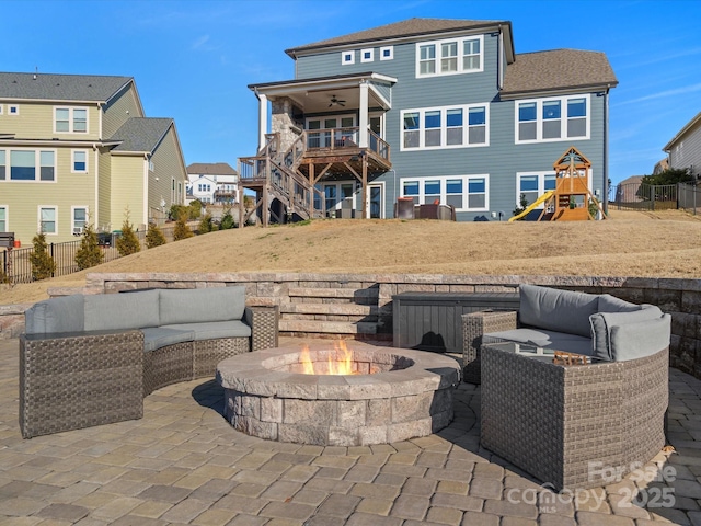 back of property with a playground, a patio, an outdoor living space with a fire pit, and ceiling fan