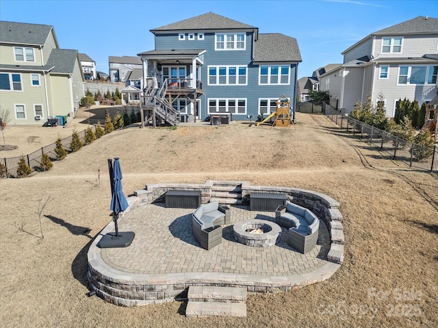 rear view of property featuring a patio area, a playground, and an outdoor fire pit