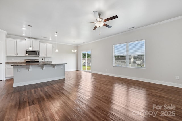 kitchen featuring pendant lighting, white cabinetry, stainless steel appliances, a kitchen breakfast bar, and an island with sink