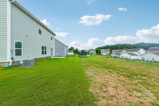 view of yard with a trampoline and central air condition unit