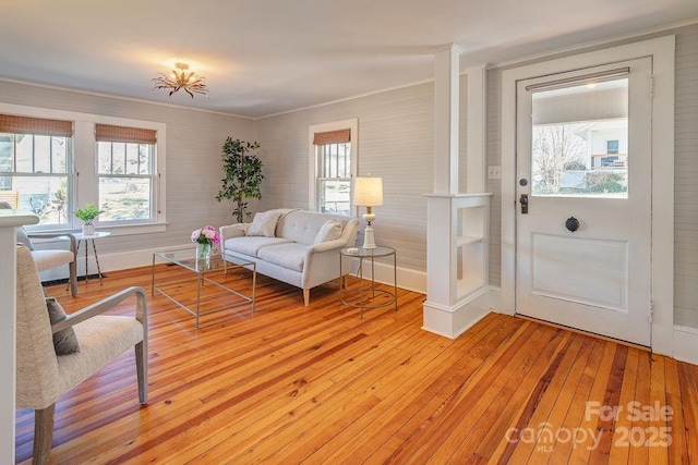 living area with light wood-type flooring, baseboards, and crown molding