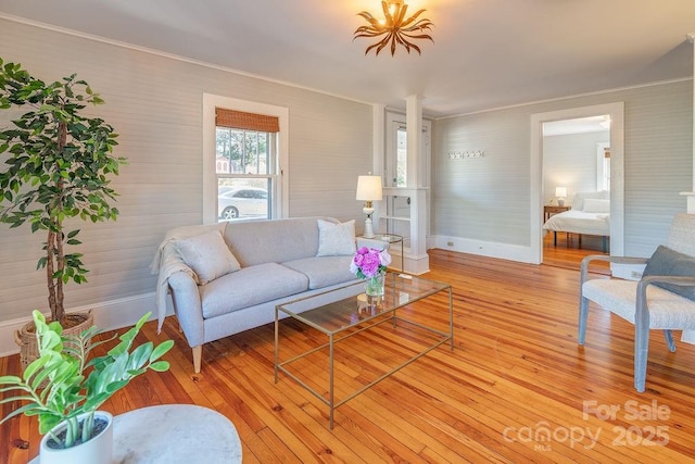 living area with crown molding, light wood finished floors, and baseboards