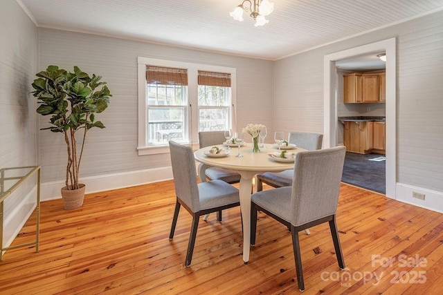 dining area with baseboards, ornamental molding, an inviting chandelier, and light wood-style floors