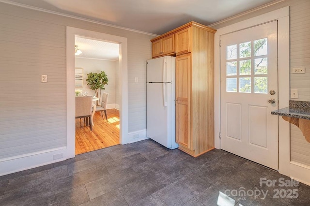 kitchen featuring ornamental molding, freestanding refrigerator, and dark stone counters