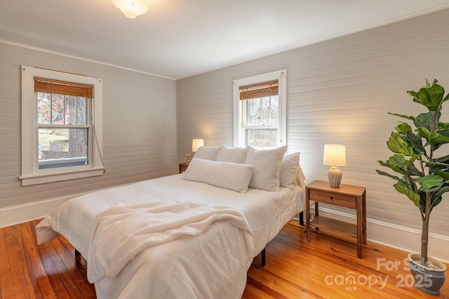 bedroom featuring crown molding, light wood finished floors, and baseboards