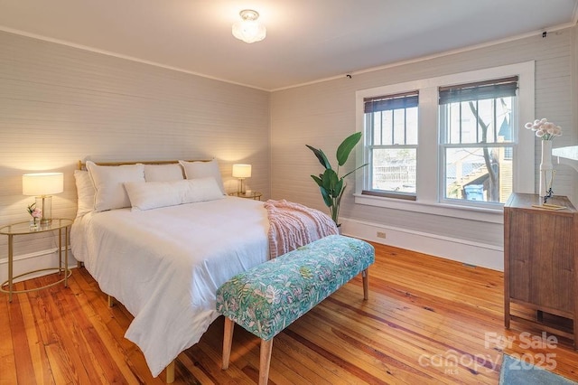 bedroom with baseboards, hardwood / wood-style floors, and ornamental molding