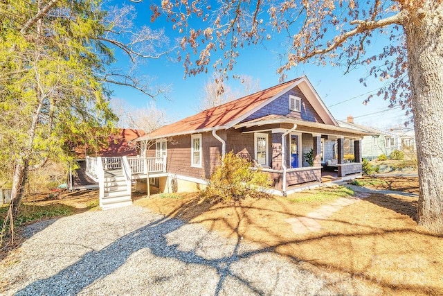 view of front of property featuring a porch and gravel driveway