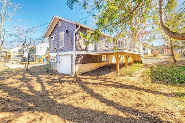 rear view of house featuring a garage, a deck, stairway, and fence