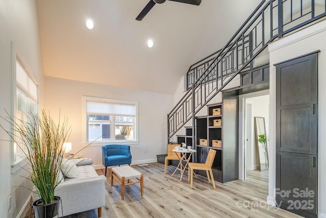 interior space with high vaulted ceiling, light wood-type flooring, stairway, and baseboards