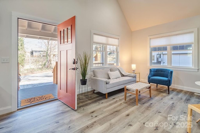 living area featuring light wood finished floors, baseboards, and high vaulted ceiling