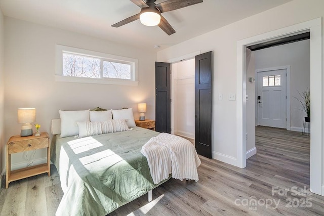 bedroom with light wood-style floors, multiple windows, and baseboards