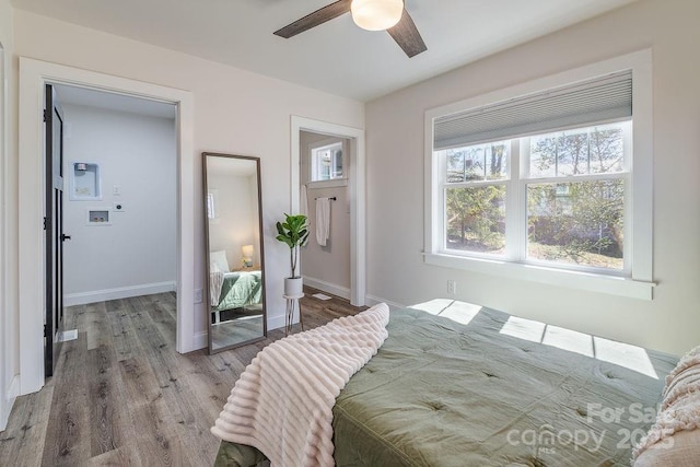 bedroom with a ceiling fan, baseboards, and wood finished floors