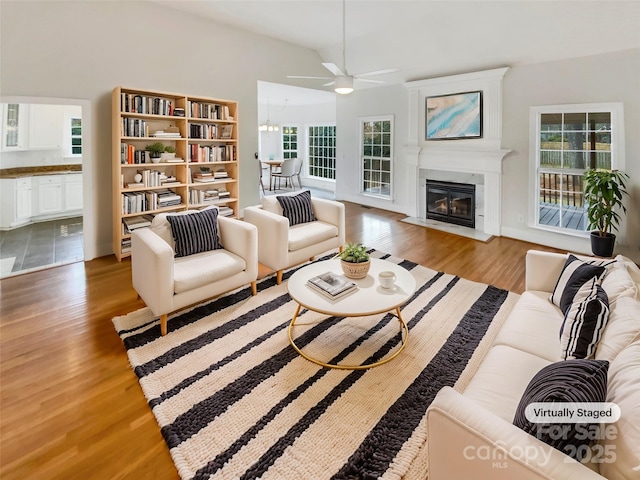 living room with ceiling fan with notable chandelier and hardwood / wood-style floors