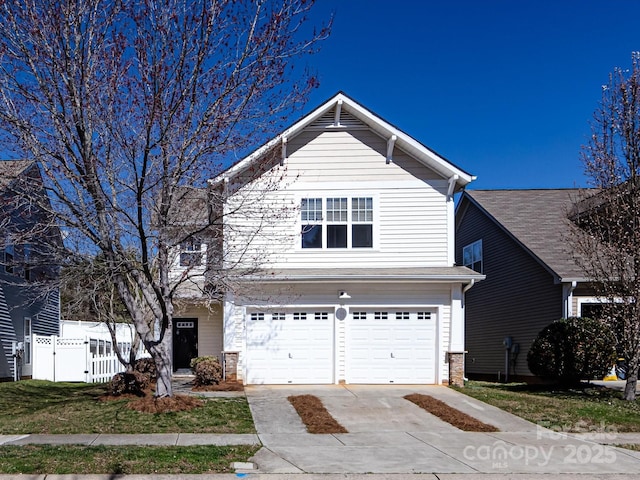 traditional-style home with concrete driveway, fence, and a garage