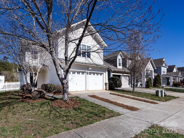 view of front facade with a residential view, fence, a garage, and driveway