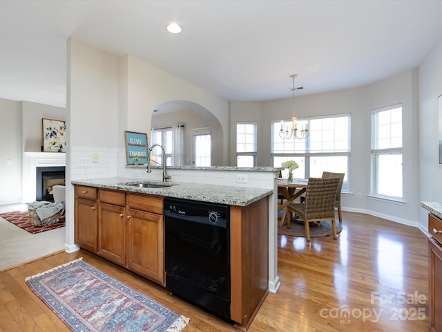 kitchen with a sink, light wood-type flooring, black dishwasher, and brown cabinetry