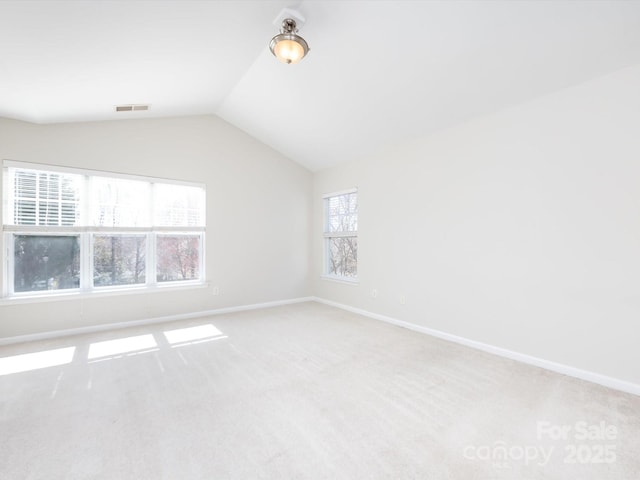 carpeted empty room featuring vaulted ceiling, baseboards, and visible vents