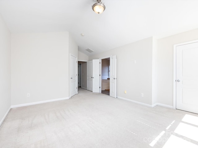 unfurnished bedroom featuring lofted ceiling, visible vents, baseboards, and light carpet