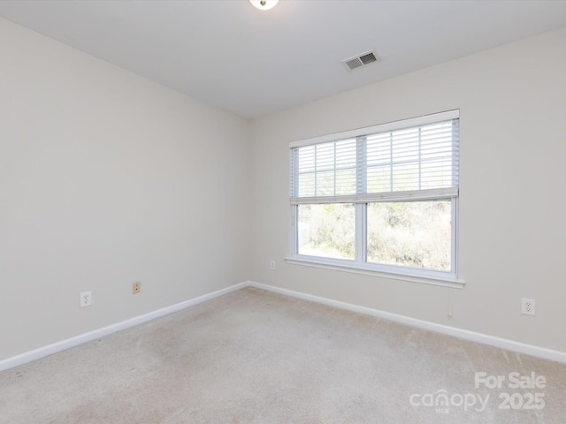 empty room featuring baseboards, visible vents, and light carpet