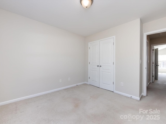 unfurnished bedroom with a closet, baseboards, and light colored carpet