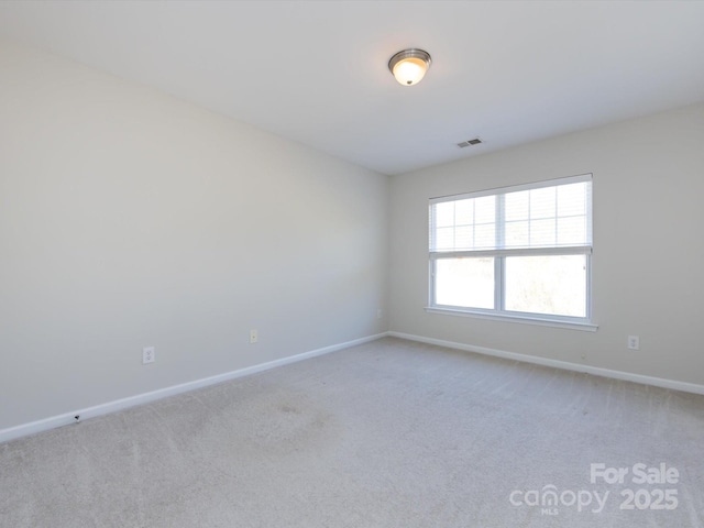 spare room featuring baseboards, visible vents, and light carpet