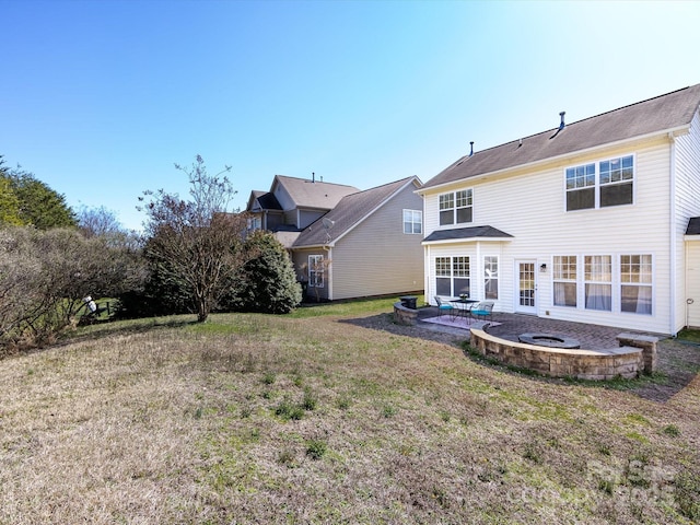 back of property with a yard, a patio, and a fire pit