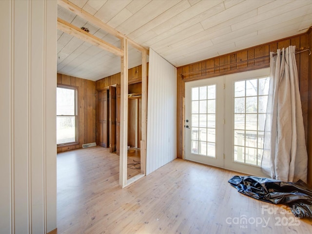 interior space with a healthy amount of sunlight, wood walls, and light hardwood / wood-style flooring