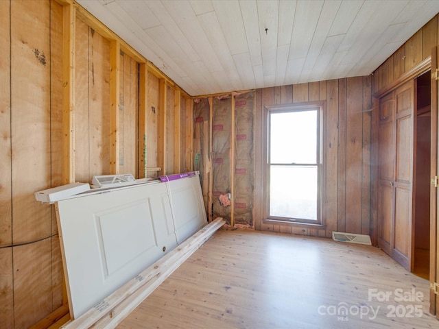 spare room with wood ceiling, wood walls, and light wood-type flooring